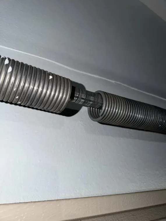 Close-up of a broken torsion spring — identifying torsion vs extension springs on Orange County garage doors