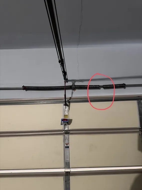 Corroded torsion spring snapped on its shaft — spring failure covered in our coastal maintenance guide