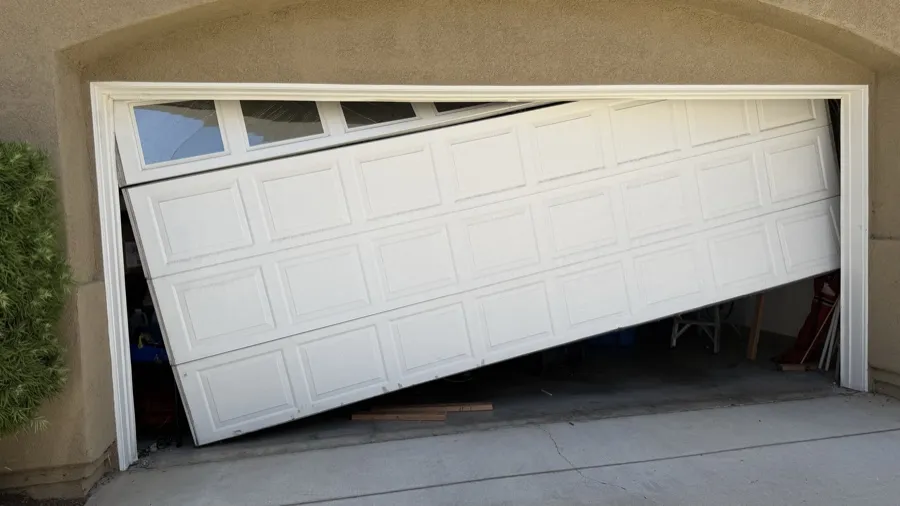 Collapsed garage door lying across an Orange County driveway — emergency off-track response scene