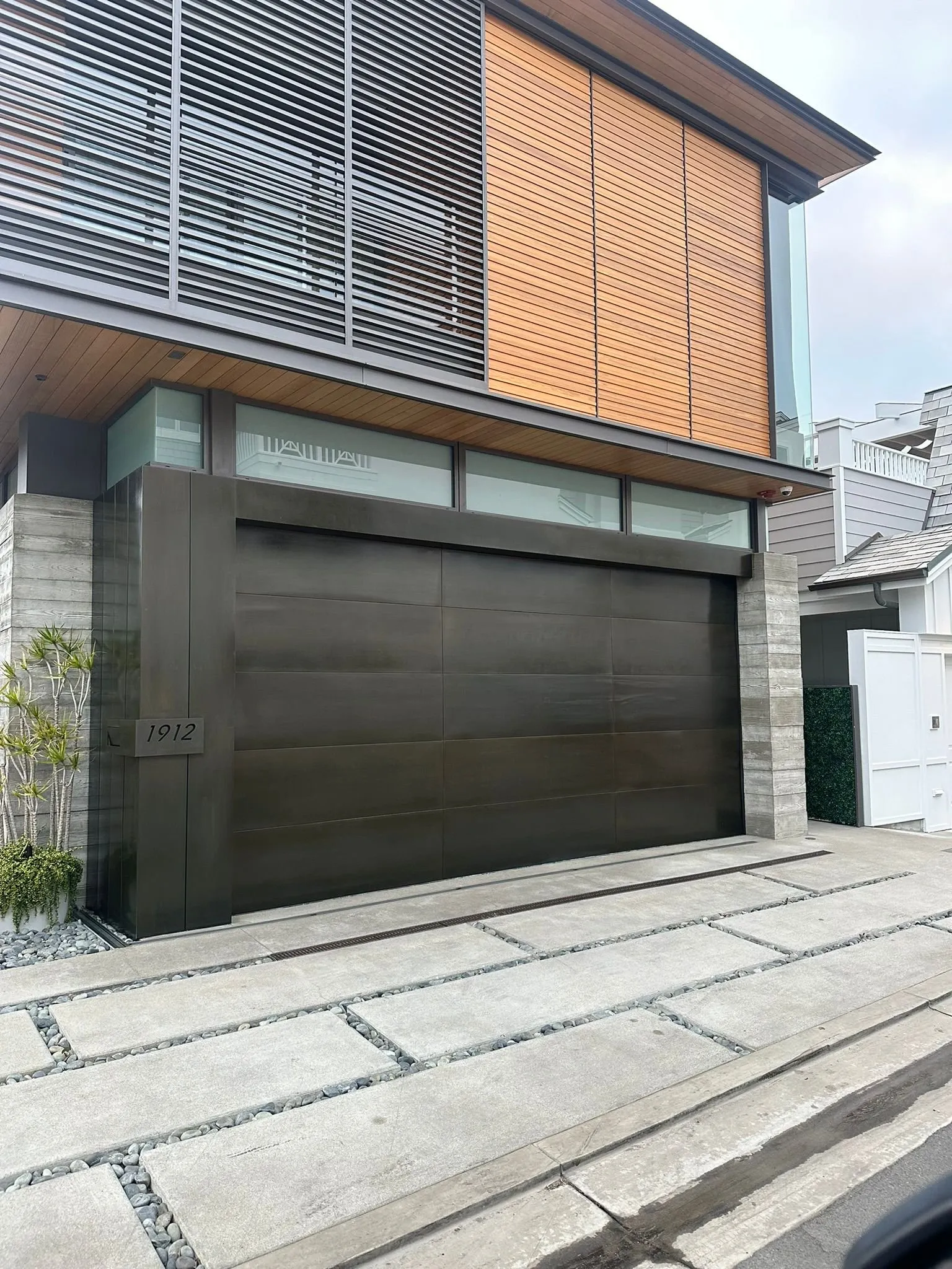 Walnut-tone modern garage door installed on a contemporary Orange County home