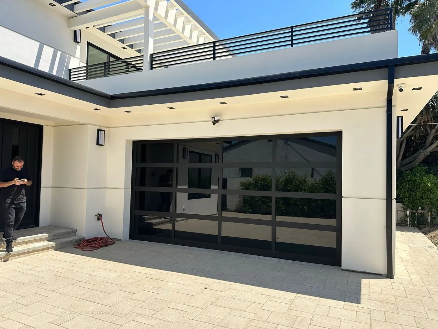 Black-frame full-view glass garage door on a white modern home — modern garage door design and installation in Orange County, CA