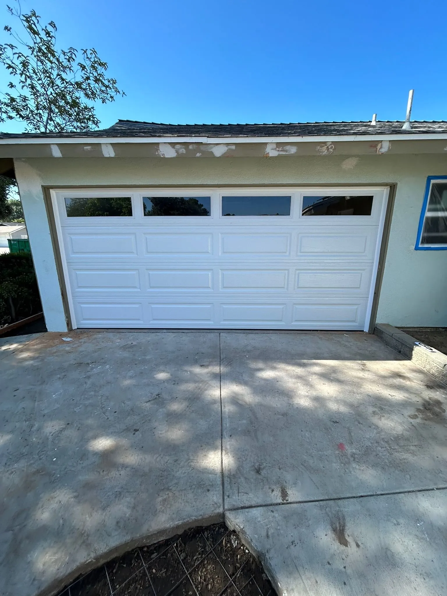 White raised-panel garage door with a window row newly installed on an Orange County home — garage door replacement service