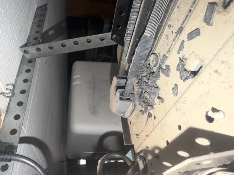 Shattered garage door panel debris and a torn hinge plate — panel replacement in Orange County, CA