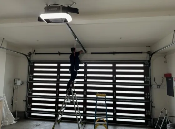 Technician repairing garage door rail sections indoors — roller and track repair in Orange County