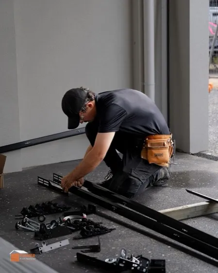 Technician assembling sliding gate track and wheel hardware on a driveway — sliding gate repair in Orange County, CA